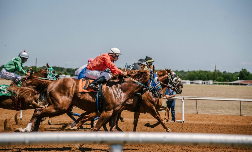 Image of horse racing, including jockeys, at a racecourse. Flutter Entertainment has posted strong revenues for the fourth quarter of 2023.
