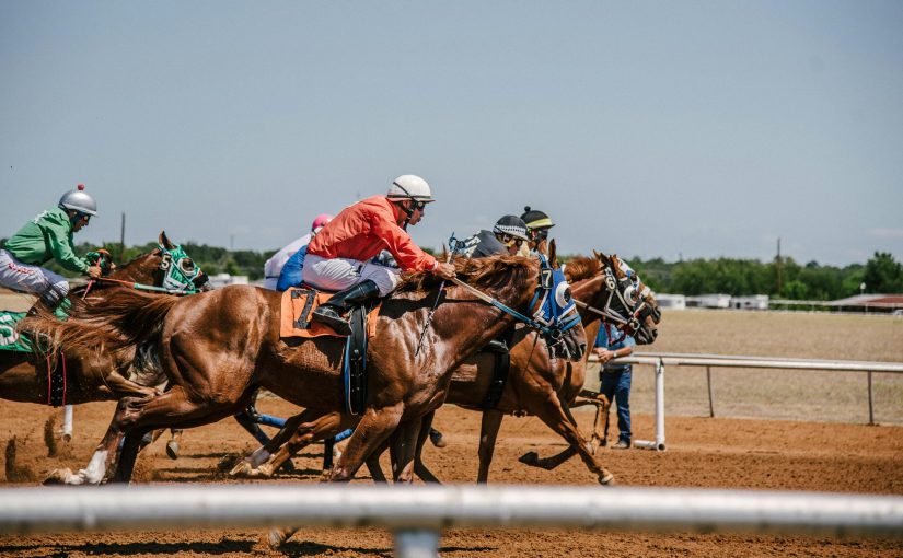 Image of horse racing, including jockeys, at a racecourse. Flutter Entertainment has posted strong revenues for the fourth quarter of 2023.