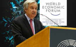 UN chief Guterres warns of 'unintended consequences' of AI. Antonio Guterres speaks behind wooden podium with World Economic Forum sign behind and AI futuristic image as background.